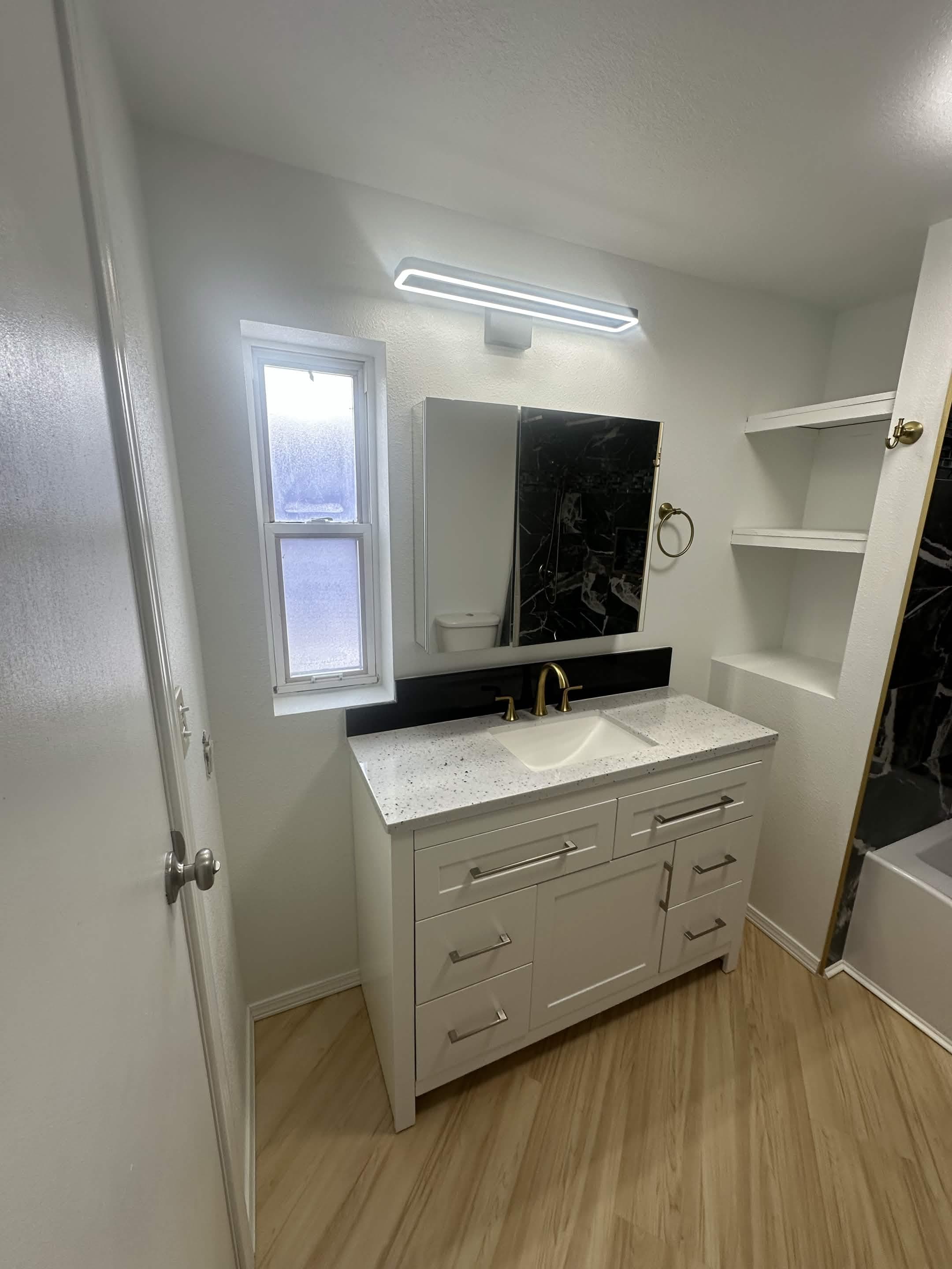 White shaker vanity with quartz countertop and modern lighting in remodeled bathroom